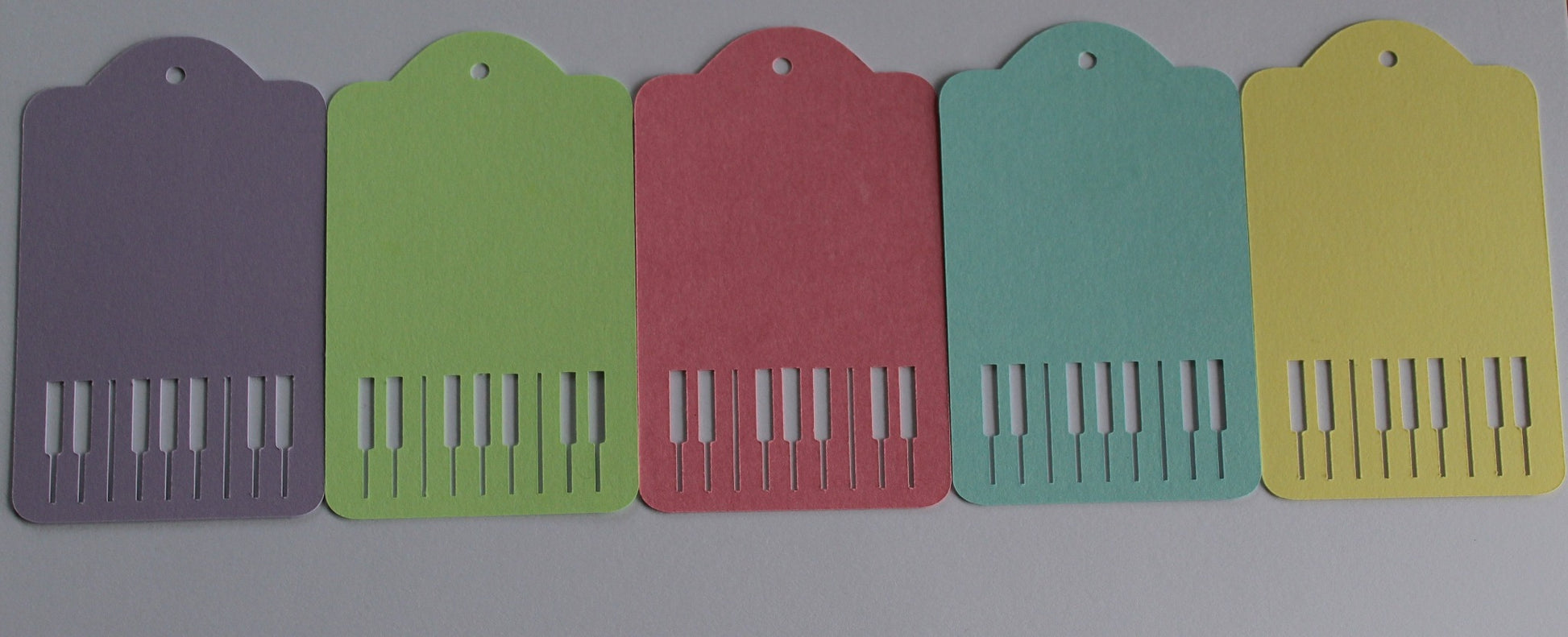 Pastel gift tags (purple, green, pink, yellow and blue) with piano keys cut out. Displayed on a white background.