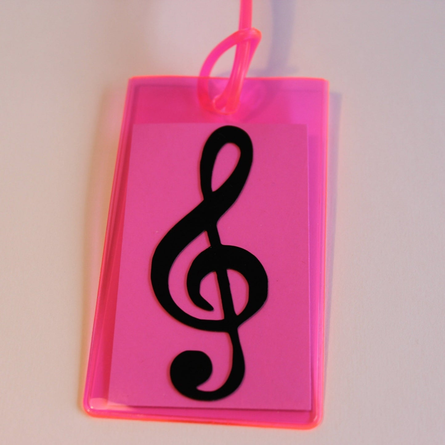 Neon pink instrument tag with black treble clef.