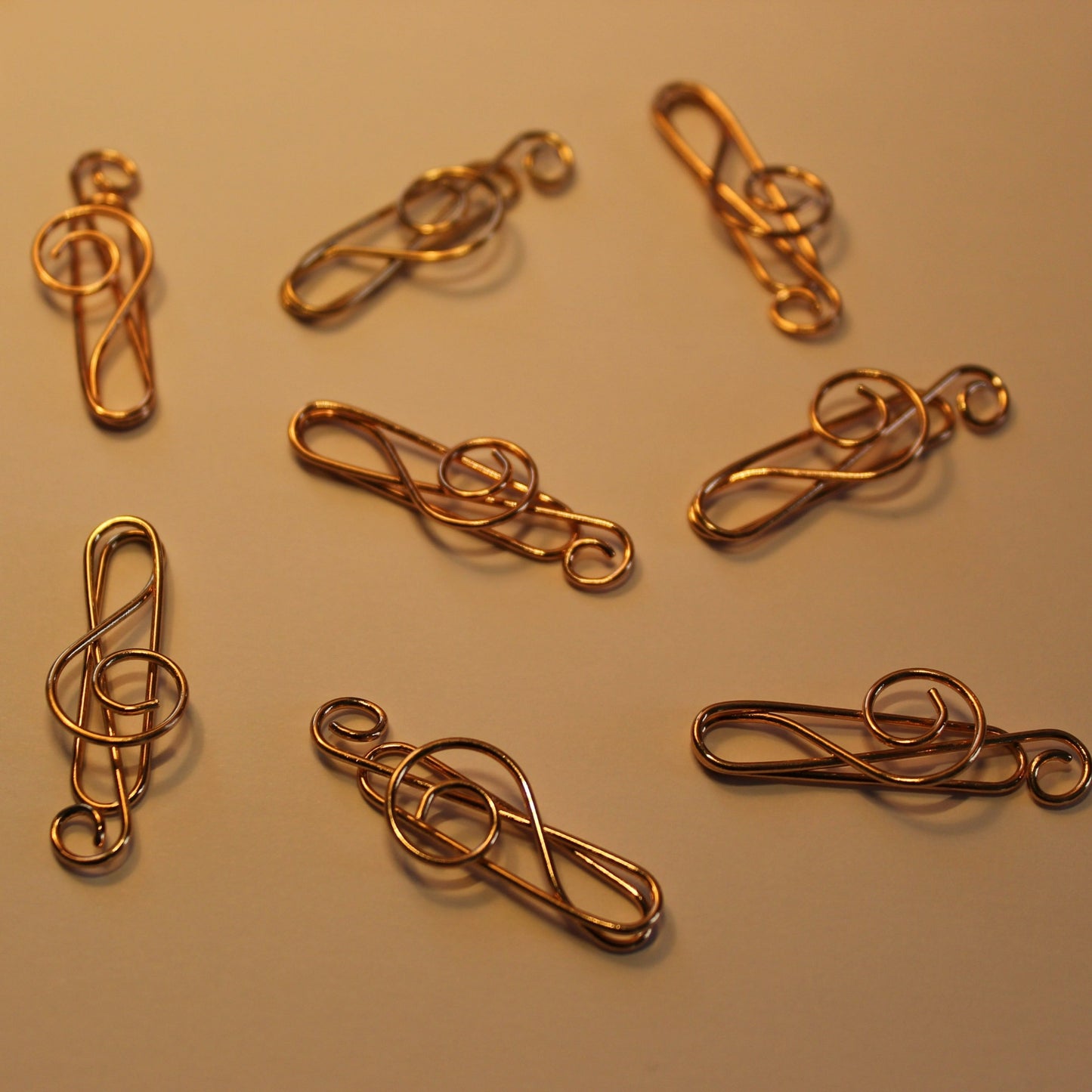 Shiny rose gold paperclips scattered on a white background.